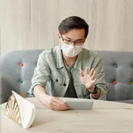 Man wearing a face mask having a video call 4031817